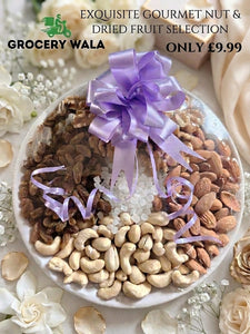 Exquisite gourmet nut and dried fruit selection on a ceramic plate with purple satin ribbon bow — cashews, almonds, brown raisins and sugar crystals