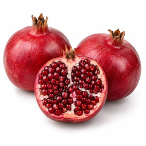 Fresh pomegranates with cut fruit on a white background