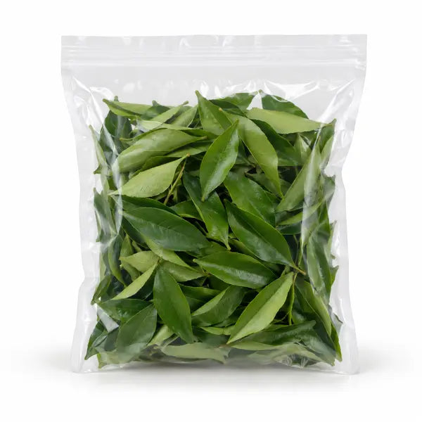 Pre-packed fresh curry leaves on a white background