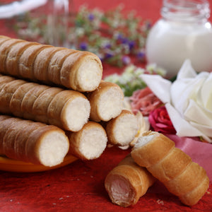 Vanilla cream-filled wafer rolls arranged beside a glass of milk